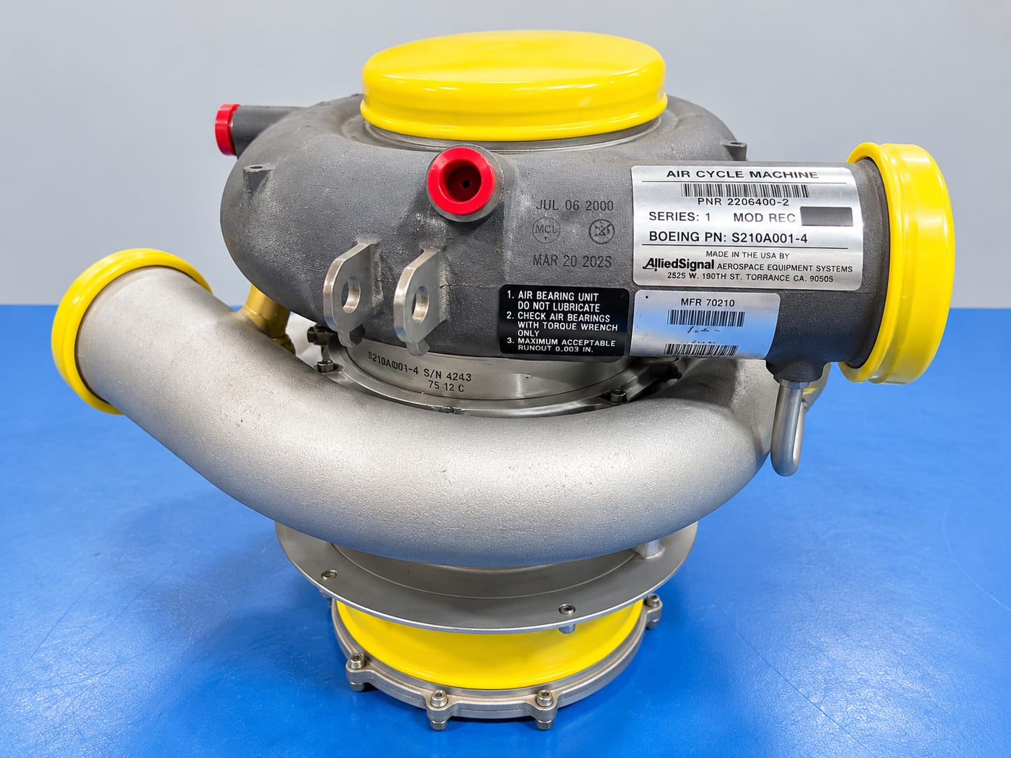 Aircraft air cycle machine with protective caps on a blue workbench